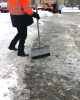 Faceless Janitor cleans the pavement from snow and ice with a shower in winter